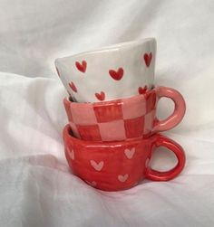 three red and white cups with hearts on them