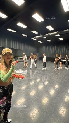 a group of people standing in a room with lights on the ceiling and one person holding a tray full of food