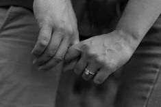 two people holding hands with their wedding rings on each other's fingers in black and white