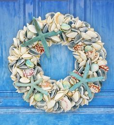 a wreath with seashells and starfish hanging on a blue door