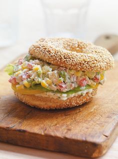 a bagel sandwich sitting on top of a wooden cutting board