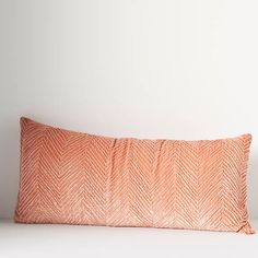 an orange pillow sitting on top of a white bed