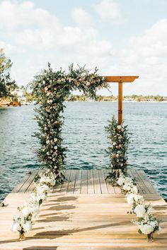 a wooden dock with flowers and greenery on it