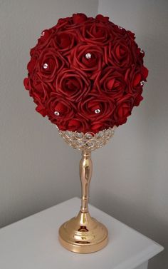 a gold vase filled with red roses on top of a white table