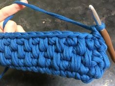 someone is crocheting the handle on a blue purse