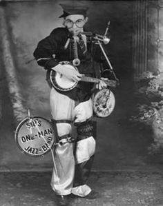 an old time photo of a man in costume playing the guitar and holding a bagpipe