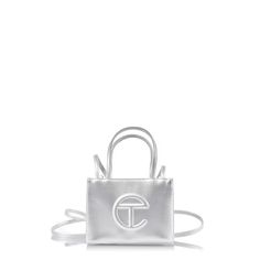 The Iconic Unisex Shopping Bag Is An Everyday Bag For Everyone. Featuring A Double Strap (Handles And Cross-Body Straps), Embossed Logo, And Magnetic Snap Closure. Made From Faux Leather And Twill Lining. Bag Is Packaged In A Drawstring Bag With Screen-Printed Logo. Materials 50% Polyurethane, 50% Polyester Dimensions Height 4 3/4", Width 6 5/8", Depth 3", Strap Drop 21", Handle Drop 4 3/4" Telfar Silver Bag, Silver Telfar, Dr Accessories, Telfar Bags, Body Straps, My Style Bags, Birthday Fits, Handbag Essentials, Silver Bags