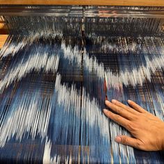 a person is weaving fabric on a loom with their hand and the other hand