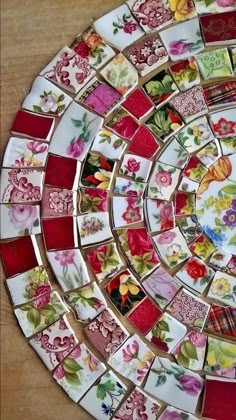 a decorative glass plate with flowers and leaves painted on it's sides, sitting on a wooden surface