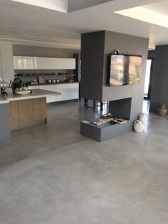 a large open living room and kitchen area in a house with concrete flooring, gray walls and ceiling