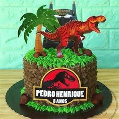 there is a cake that has a dinosaur on it and palm trees in the background