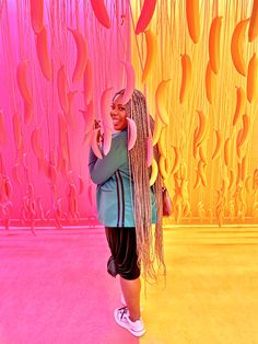 a woman standing in front of a pink and yellow wall