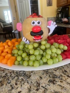 a plate full of grapes, carrots and fruit with a face made out of a man's head