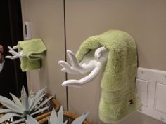 a towel hanging on the wall next to a light switch and some plants in a basket