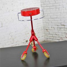 a red stool sitting on top of a black table