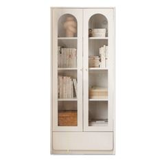 a white bookcase with glass doors and shelves on each side, in front of a white wall