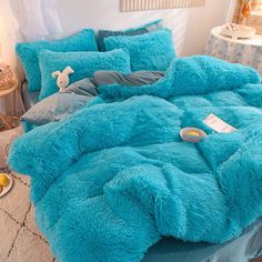 a bed covered in blue fluffy blankets and pillows