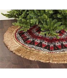 a small christmas tree in a potted planter on a wooden floor next to a rug