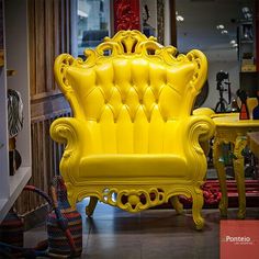 a yellow chair sitting next to a table in a room filled with other furniture and accessories