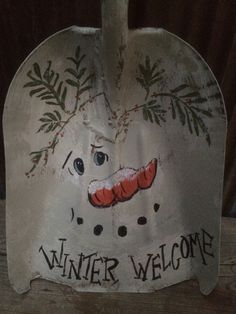 a sign that says winter welcome with a snowman's face painted on it