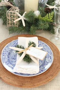 a place setting with blue and white plates, napkins and candles on the table