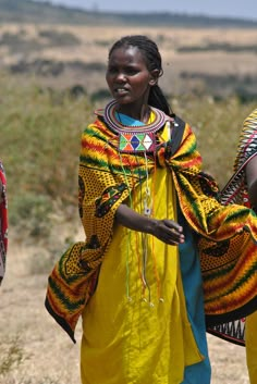 three women in brightly colored clothing walking down a dirt road