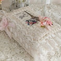 a white lace tablecloth with pink flowers on it and a small candle holder in the background