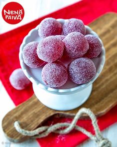 powdered sugar balls in a white bowl on a red place mat and wooden cutting board