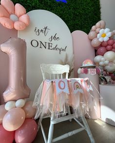 a pink and white birthday party set up with balloons, streamers, decorations, and an inflatable number one sign