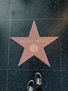 a person standing in front of a star on the hollywood walk of fame with their feet up