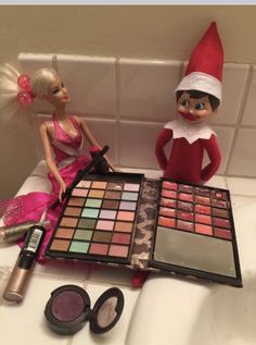 two elf dolls sitting on a counter with makeup