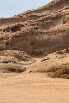 a giraffe standing in the middle of a dirt field next to large rocks