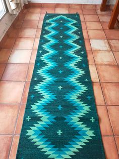 a blue and green rug sitting on top of a tile floor next to a window