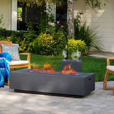 a fire pit sitting on top of a brick patio next to a chair and table