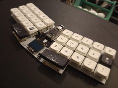 a computer keyboard that has been broken and is sitting on a table with other parts attached to it