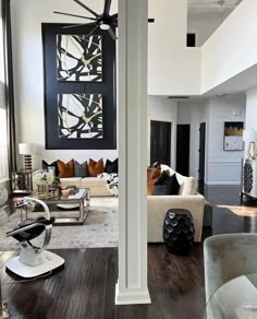 a living room filled with furniture and a ceiling fan in the middle of an open floor plan