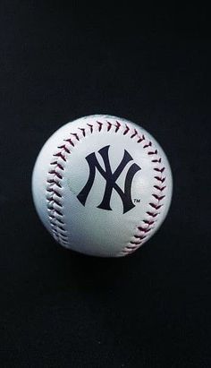 a baseball with the new york yankees on it sitting on a black surface in front of a dark background