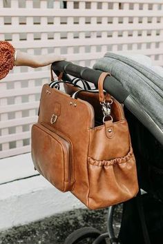 a brown purse hanging from the handle of a stroller