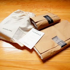 two brown bags sitting on top of a wooden floor next to a white paper bag