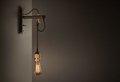 a black lamp hanging from the side of a gray wall next to a light fixture