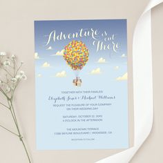 a blue and white wedding card with a hot air balloon floating in the sky above it