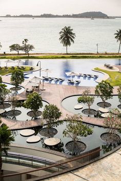 an aerial view of a large pool with umbrellas and trees in the foreground