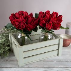 two vases filled with red flowers sitting on top of a table