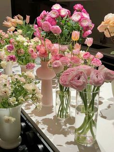 several vases filled with pink and white flowers on a counter top next to each other