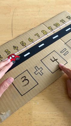 a person is making a cardboard car on the road with numbers and cars drawn on it