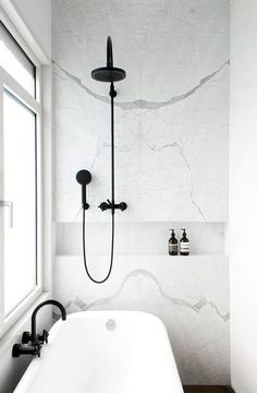 a white bath tub sitting under a window next to a wall mounted faucet