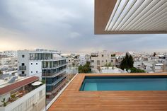 a man standing on top of a roof next to a swimming pool and tall buildings