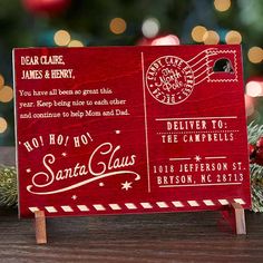 a red wooden sign sitting on top of a table next to a christmas tree with lights in the background