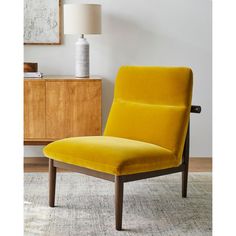 a yellow chair sitting on top of a rug next to a lamp