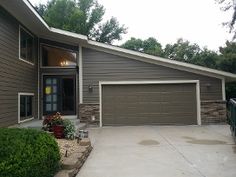 a house with two garages in front of it and landscaping around the driveway area